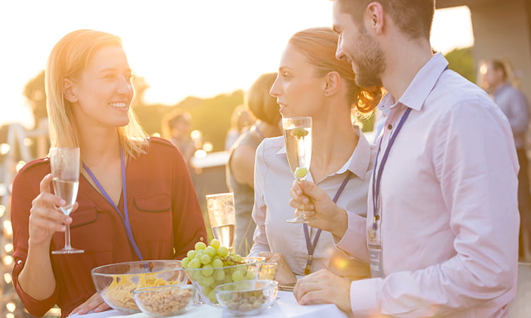 Employees with lanyards toast drinks at an outdoor corporate event